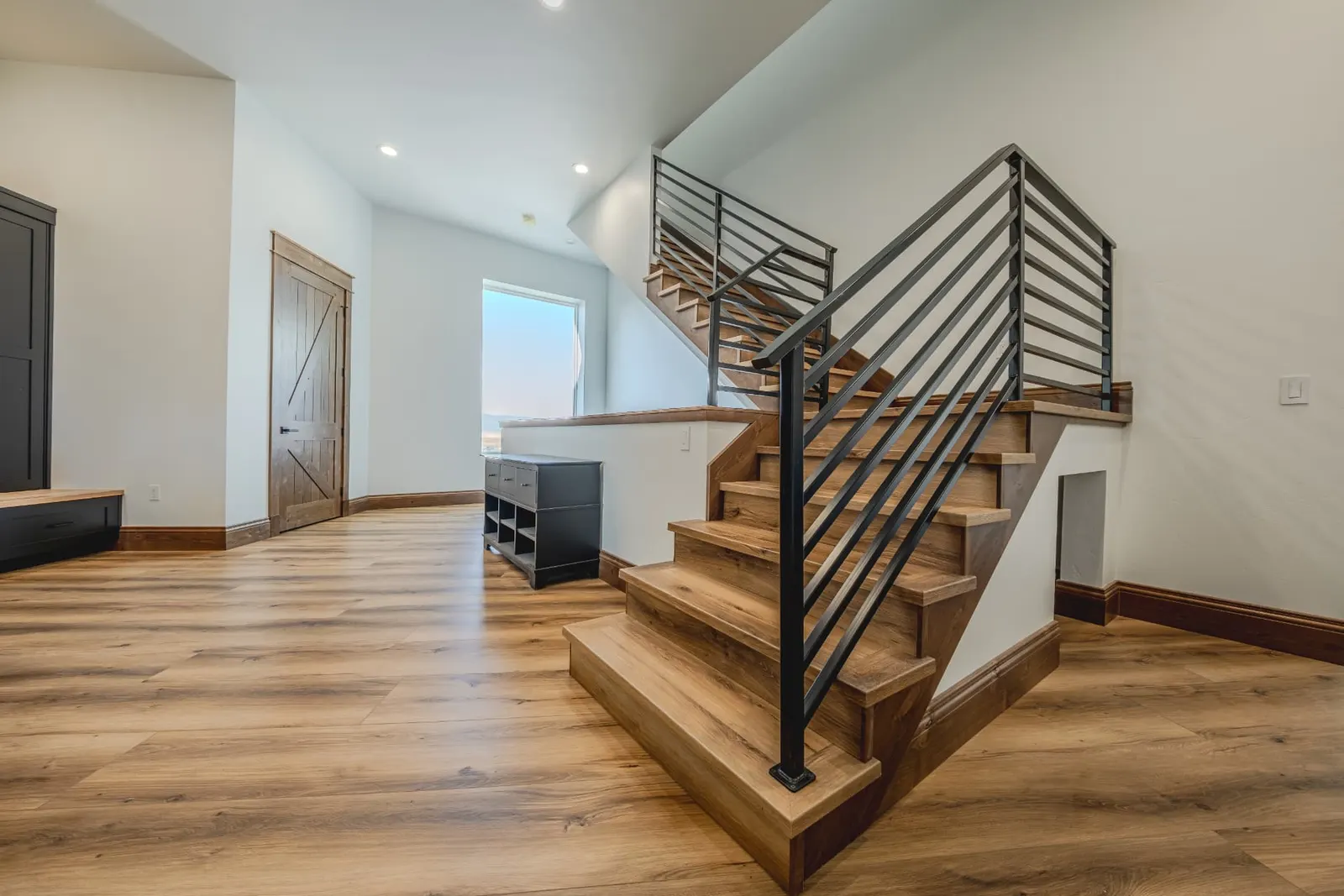 LVP stair run with matching wide-plank floor and black metal railing