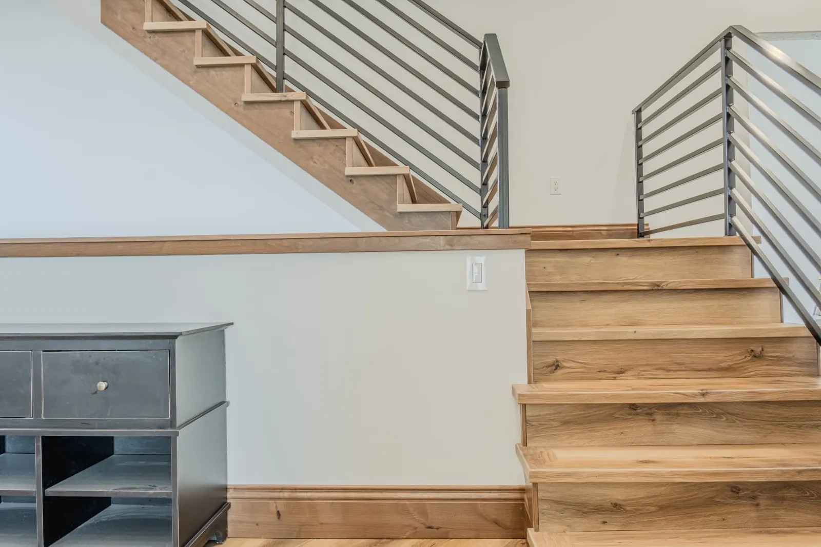 Two stair runs in oak meeting at a shared landing wall