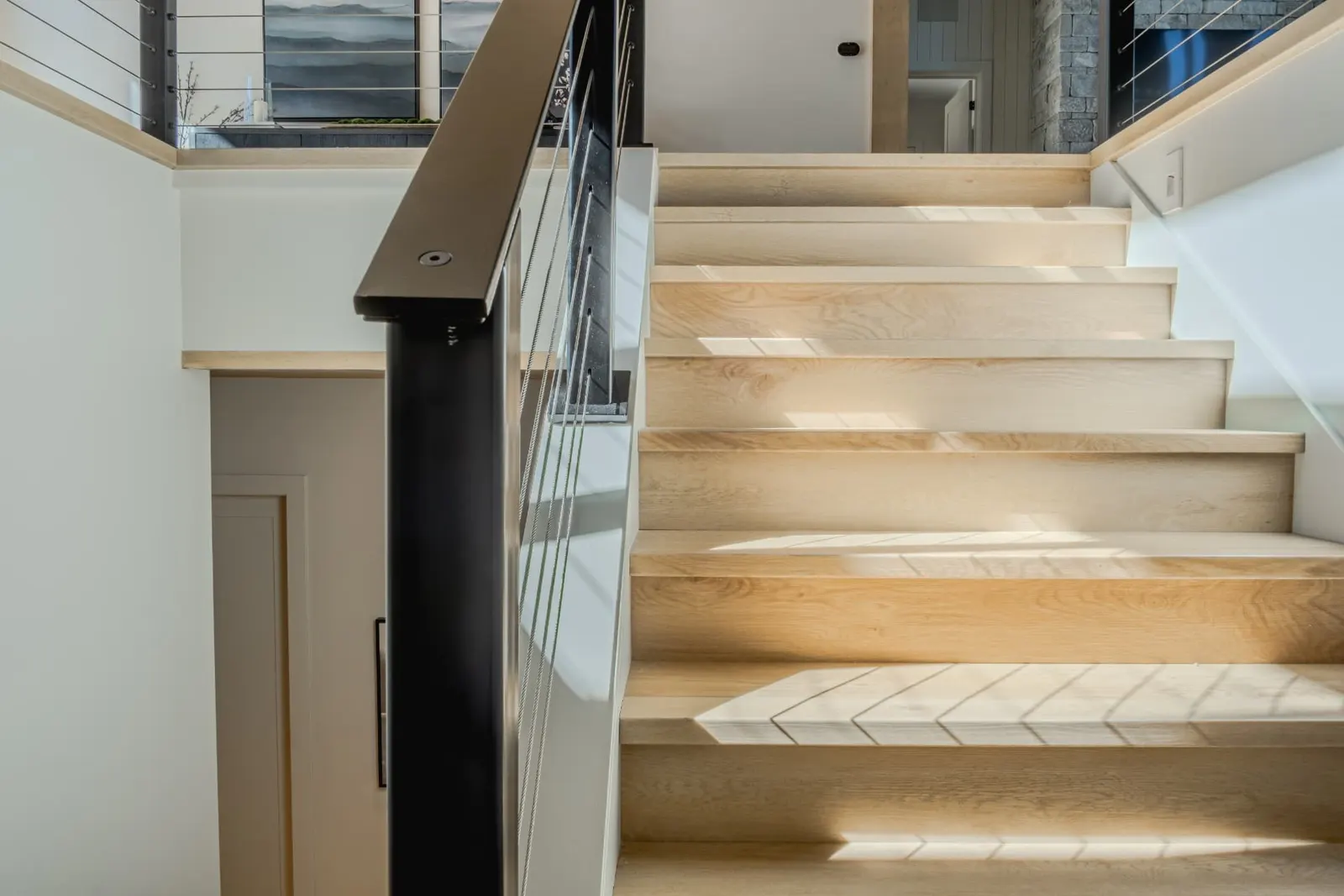 Sunlit white oak stair treads with cable railing